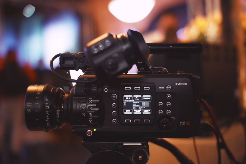 Close-up of a professional video camera in a studio environment, showcasing lens and controls.