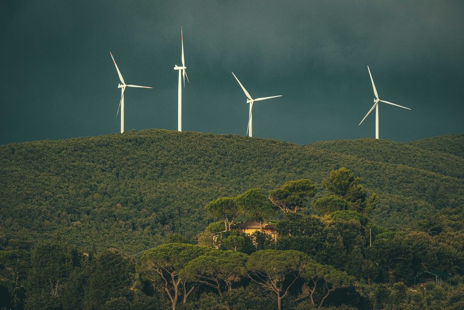 Wind turbines stand above lush green hills, showcasing renewable energy in nature.