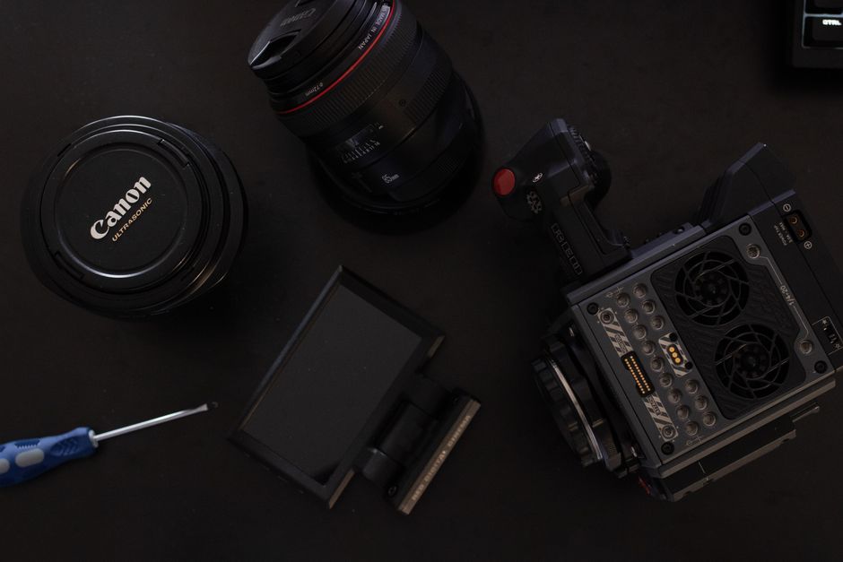 A collection of camera equipment including lenses and accessories on a dark surface.