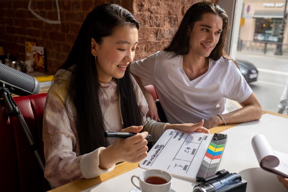 Young adults enjoy a creative filmmaking session in a cozy café setting with a clapperboard.