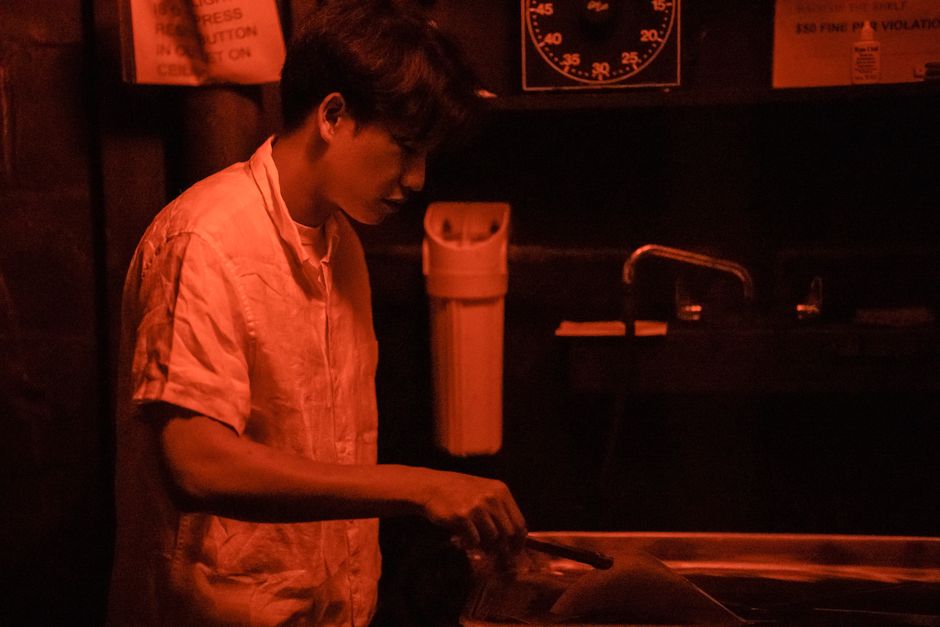 A photographer processes images in a dimly lit darkroom, utilizing traditional techniques.