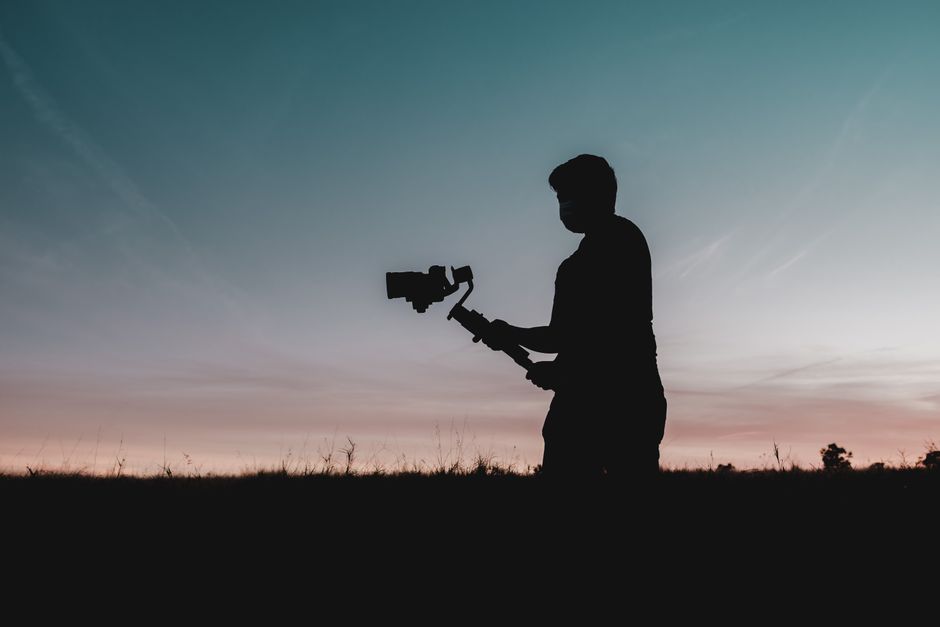 Silhouette of a man holding a camera while filming at sunset in Orlando.