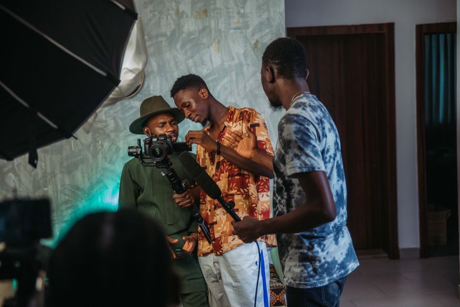 Three men collaborating on a film set indoors, engaged with camera and sound equipment.
