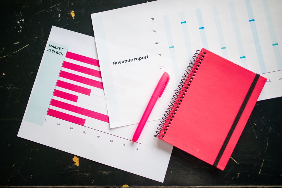 Overhead shot of a desk with charts, a red notebook, and a pen for business analysis.