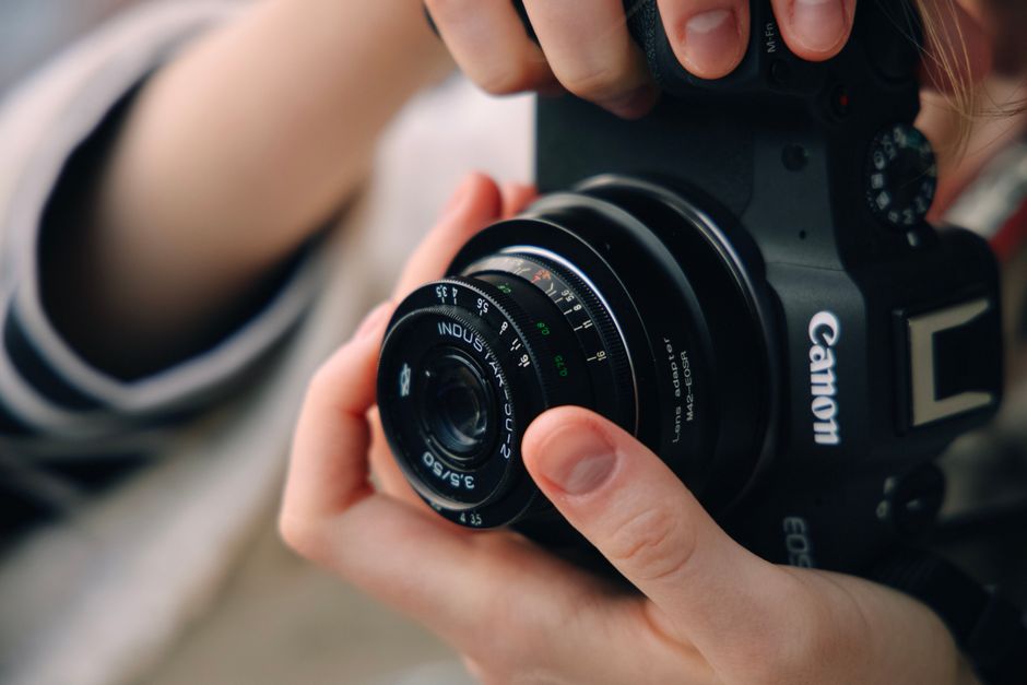 Close-up of hands adjusting a vintage lens on a modern Canon camera