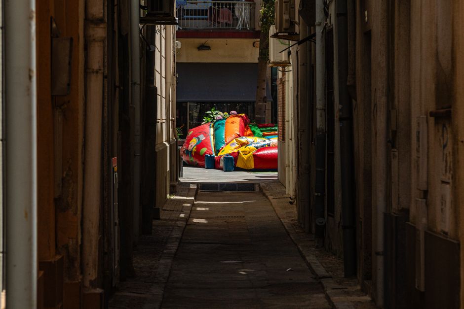 Colorful deflated inflatable bouncer resting at the end of a narrow alleyway.