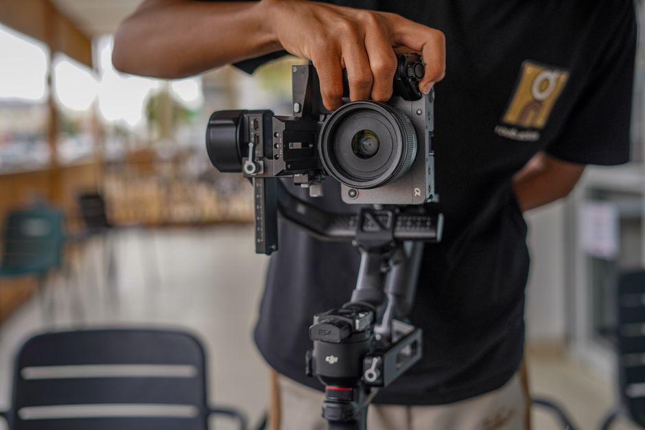 Close-up of a photographer adjusting a camera on a gimbal stabilizer indoors, showcasing professional videography equipment.