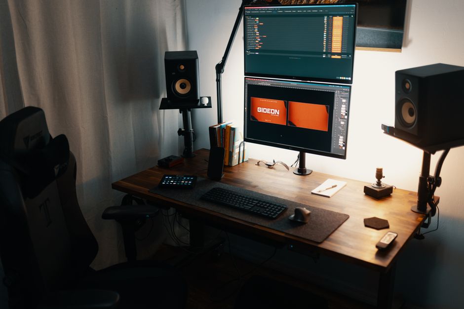 A well-organized home office featuring dual monitors, speakers, and stylish wood desk perfect for design and tech work.