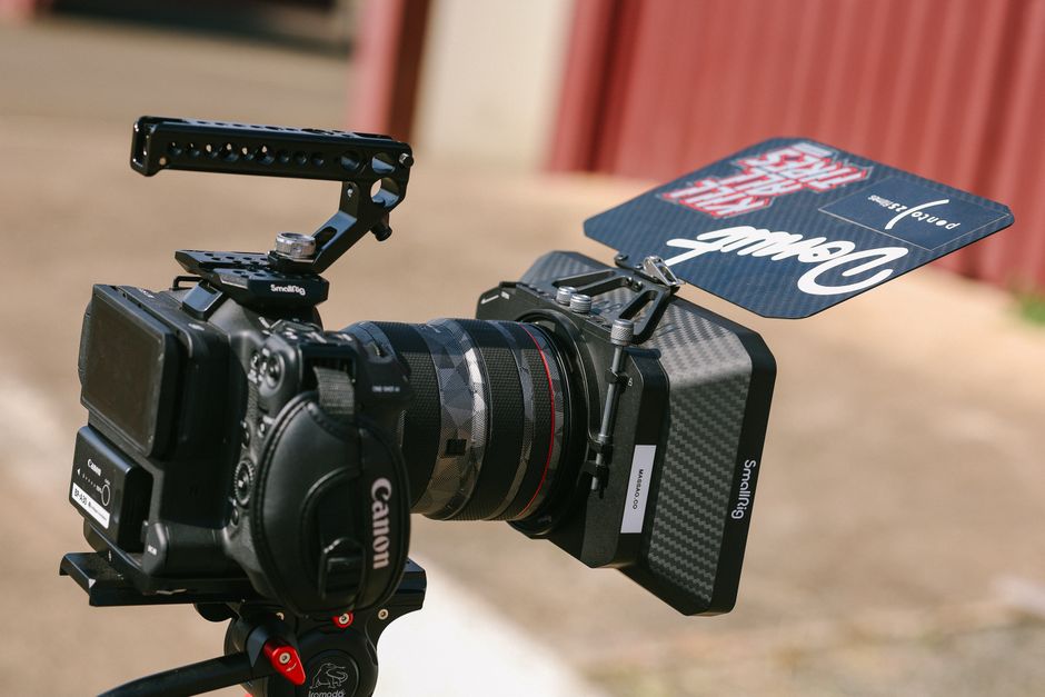Close-up of a Canon video recording setup with follow focus and matte box outdoors.