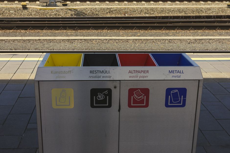 Color-coded recycling bins at a train station, promoting waste separation and environmental sustainability.