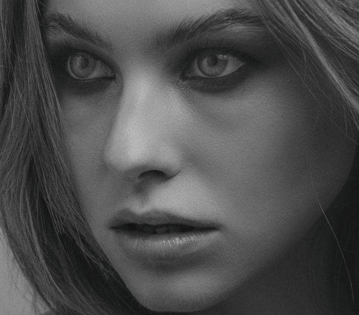 Close-up black and white portrait highlighting a woman's intense gaze and facial features.