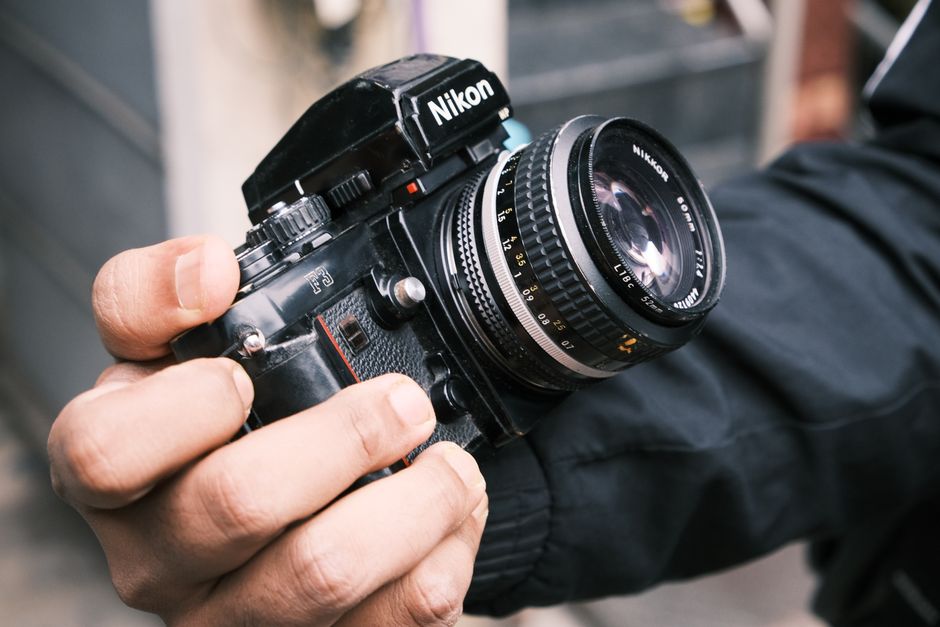 Close-up of a vintage camera being held by a person outdoors, showcasing classic photography equipment.