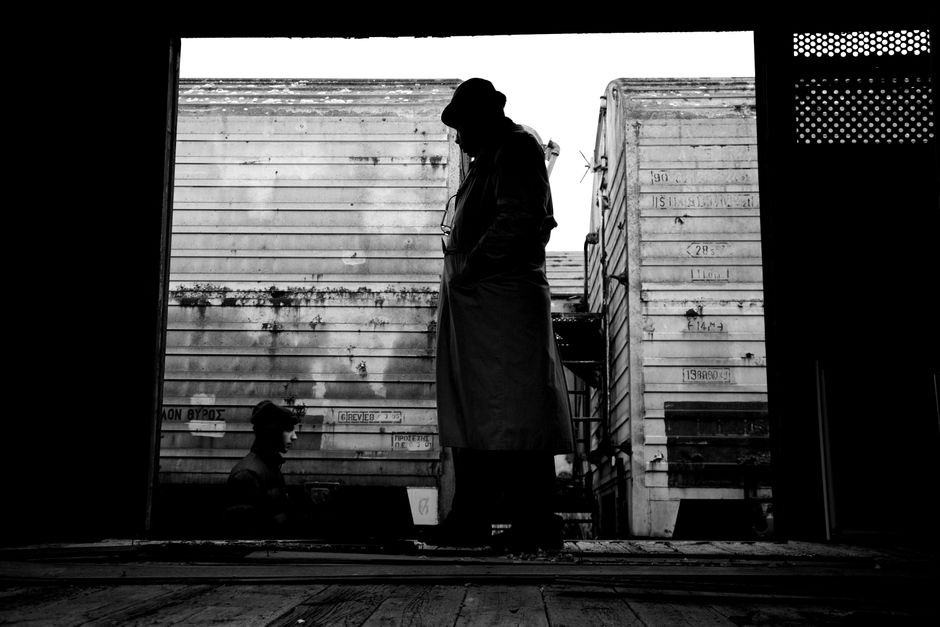 Silhouette of a man in a trench coat reveals solitude by train wagons.