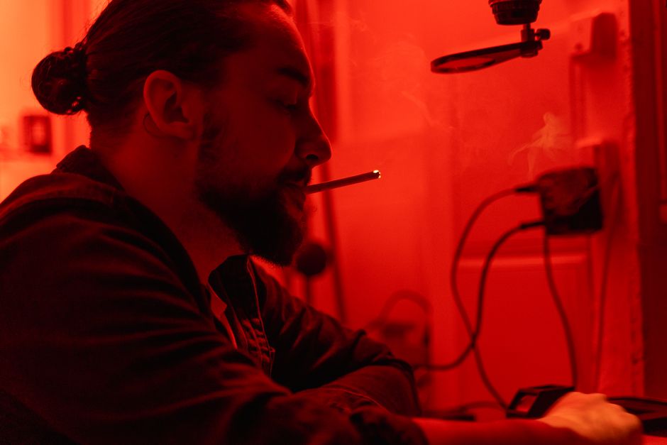 A dramatic silhouette of a man smoking in a red-lit darkroom, creating a vintage atmosphere.