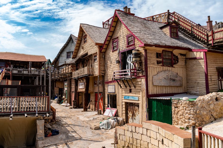 Scenic view of Popeye Village, Mellieħa, Malta, with rustic wooden architecture on a sunny day.