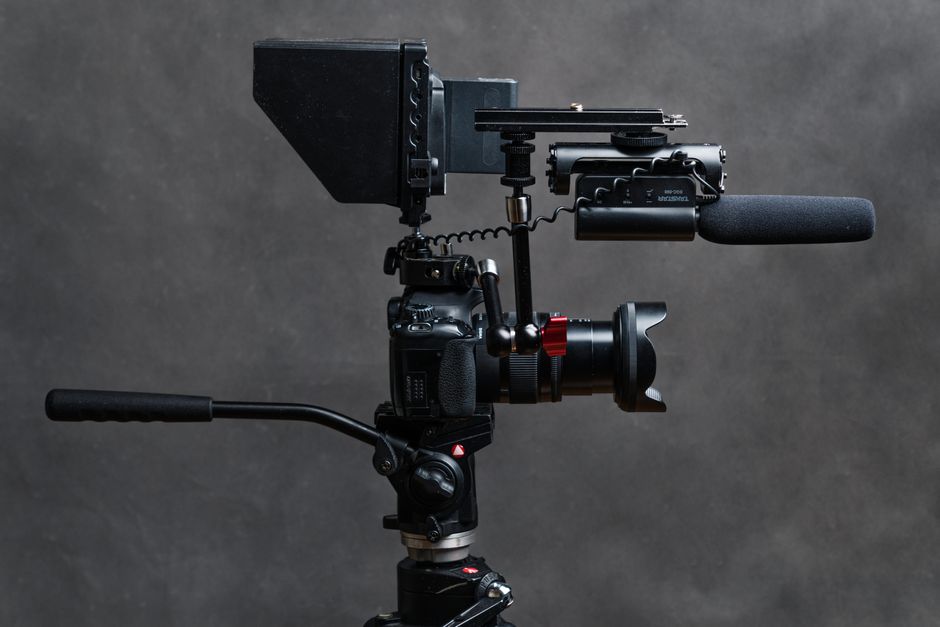 Close-up studio shot of a DSLR camera with video accessories including a microphone and tripod.