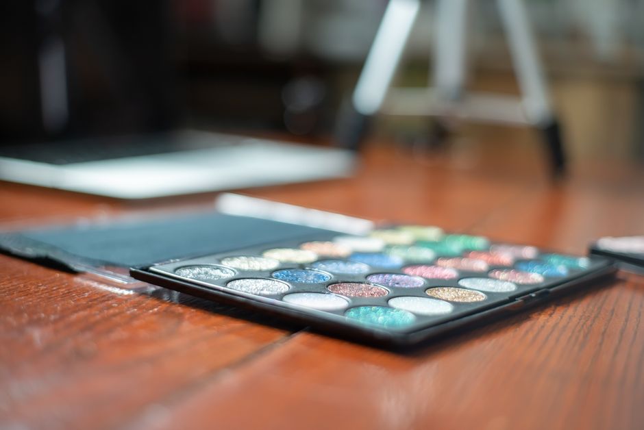 Colorful eyeshadow palette on a wooden table, ideal for beauty and makeup enthusiasts.