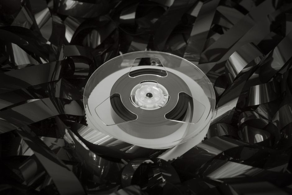 Close-up of a vintage cassette reel surrounded by tangled tape, evoking nostalgia and retro vibes.