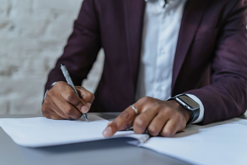 Close-up of a man signing documents in an office. Business-focused and professional environment.