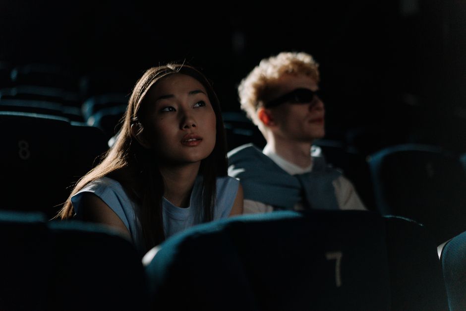 Couple seated in a dimly lit movie theater enjoying a film together.