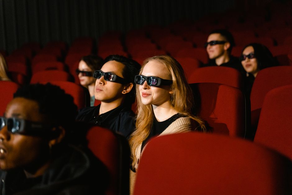 People in a cinema wearing 3D glasses, watching a film attentively.