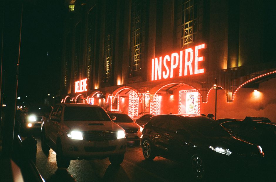 Traffic under glowing neon signs in Bangkok, creating a dynamic urban night scene.