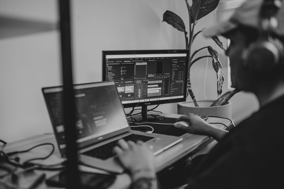 Person working remotely with dual monitors in a minimalist, monochrome setup.