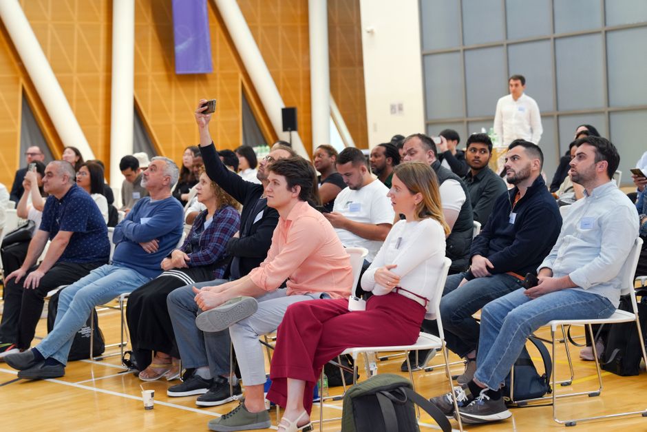 A diverse audience attentively listens during an indoor seminar, showcasing a collaborative learning environment.