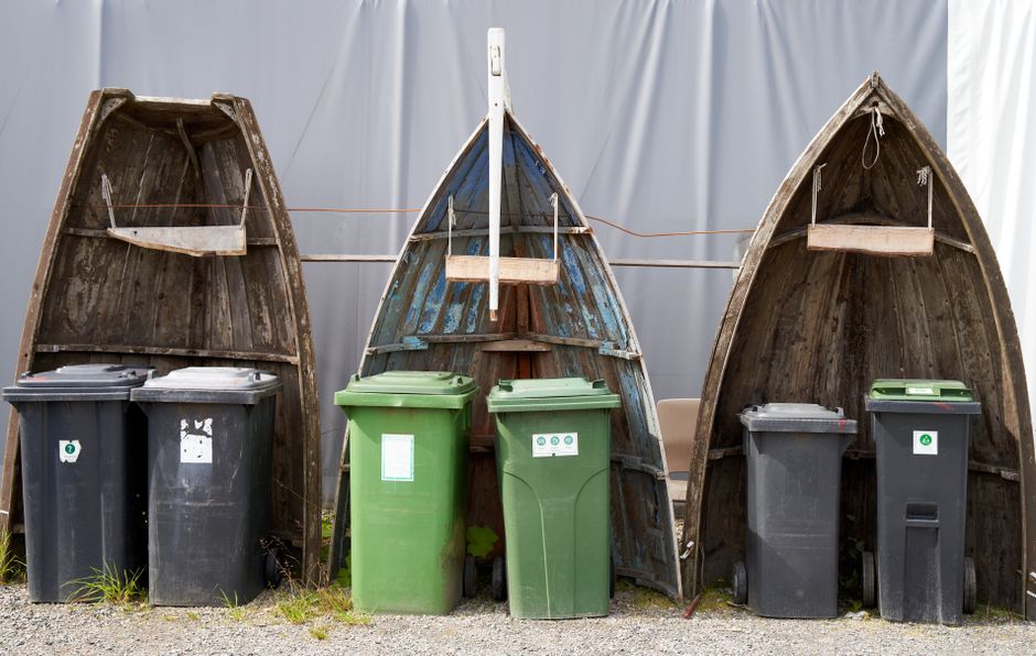 Recycling bins placed within upcycled boat hulls create an artistic outdoor installation.