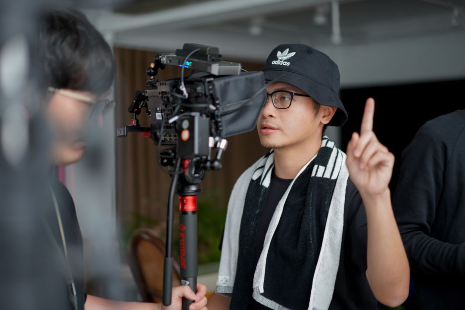 Director focused on managing film equipment and instructing crew indoors.