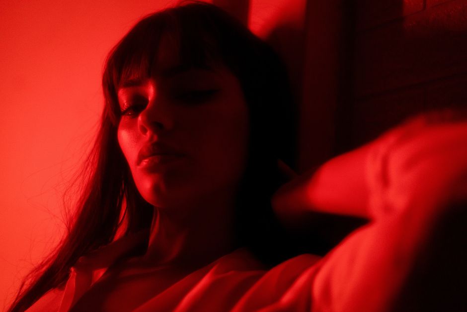 Dramatic portrait of a woman in red lighting, evoking a mysterious and artistic mood.