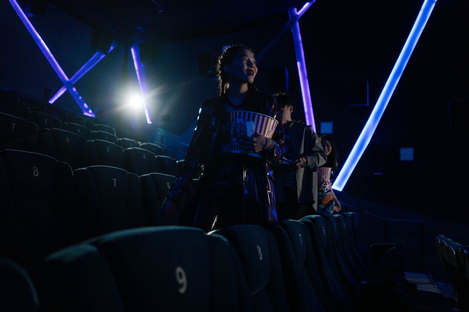Young adults enjoying popcorn in a private cinema with neon lights.