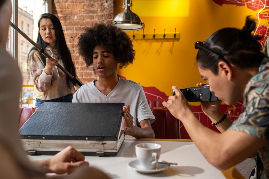 A diverse group filming an engaging scene inside a trendy cafe.
