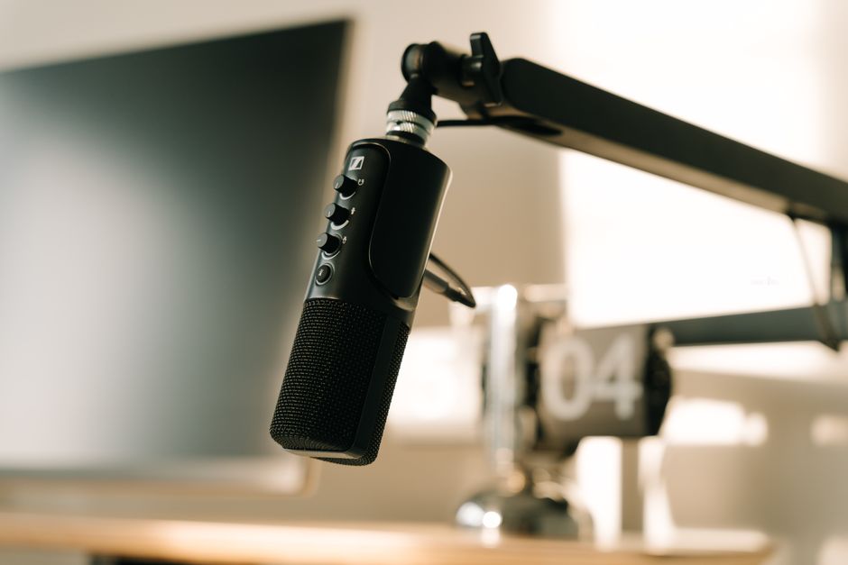 A studio microphone on a boom arm in soft, warm lighting, perfect for podcasts or voiceovers.