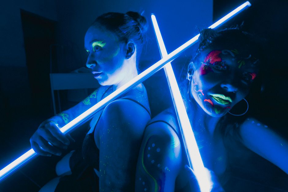Women illuminated by neon colors and UV light create a vibrant, artistic scene in Mexico City.