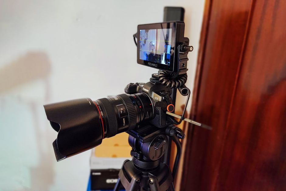 Close-up of a professional camera on tripod with external monitor indoors.