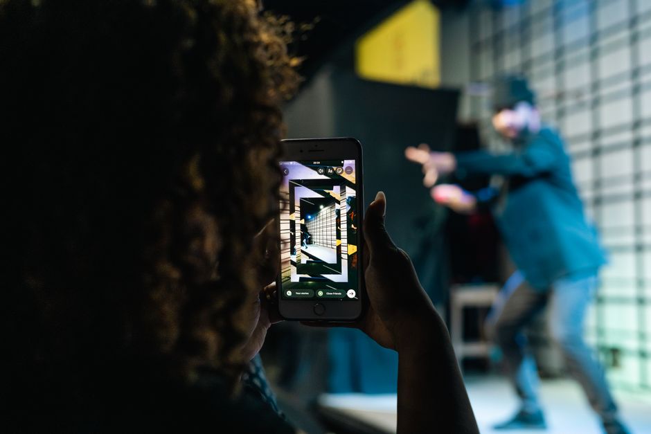A person takes a photo of a live performance using a smartphone, highlighting modern technology in event capturing.