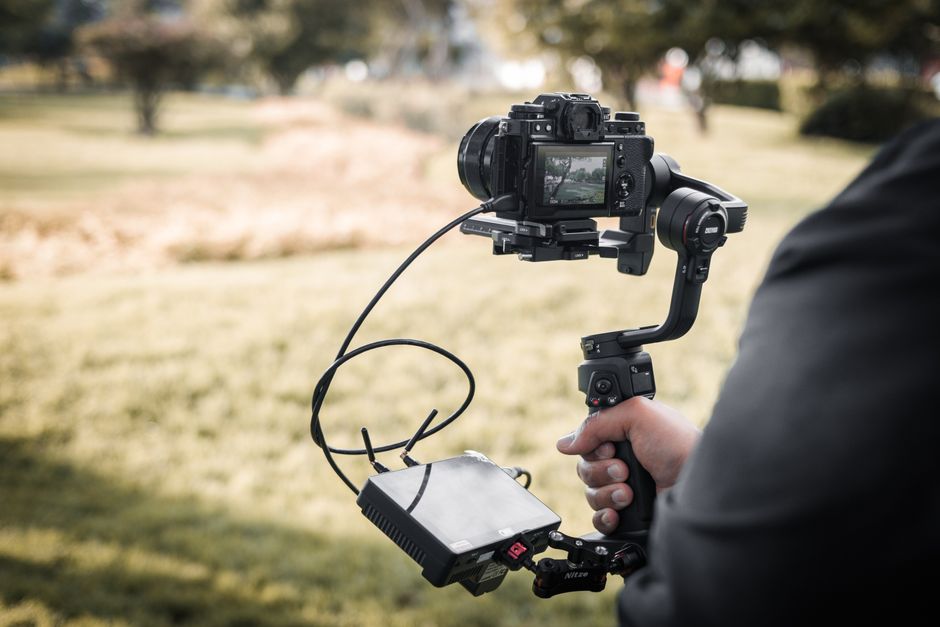 Person using camera stabilizer and monitor captures outdoor nature scene in Lima, Peru.