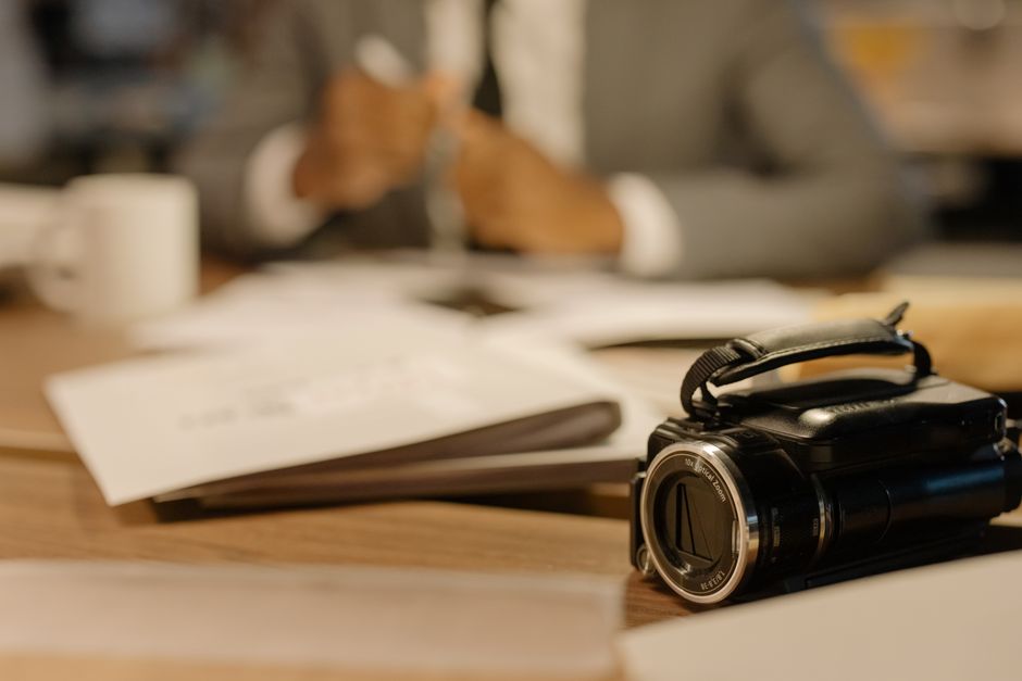 A camcorder on a desk in an office setting, capturing professional work activities.