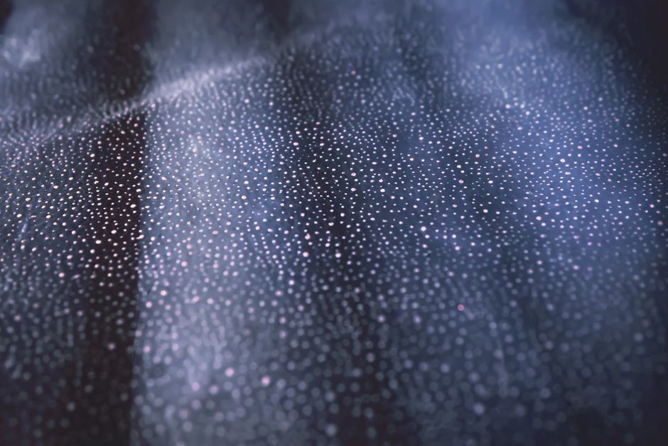 Close-up of shimmering bokeh lights on a textured dark surface creating an abstract pattern.