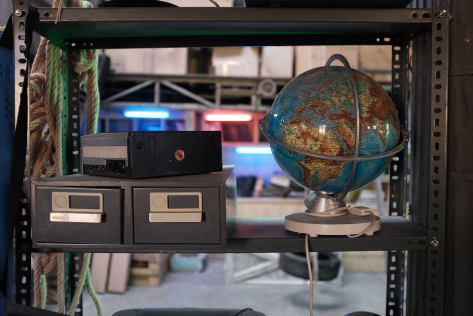 A vintage globe and retro electronic devices on industrial shelves in a warehouse setting, ideal for nostalgic themes.