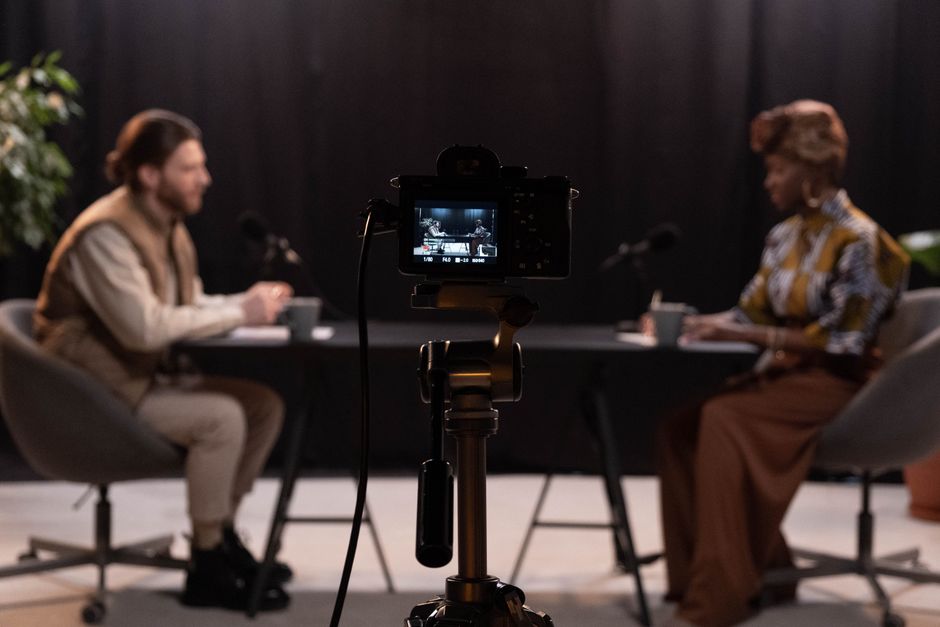 Two hosts recording a podcast in a studio setting with professional equipment.