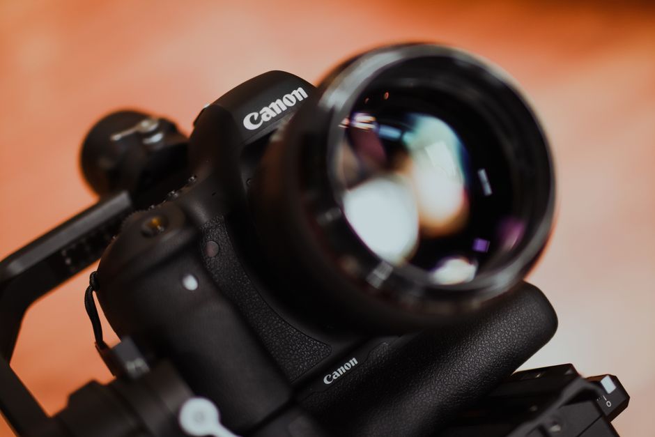 Detailed close-up shot of a Canon camera lens with blurred reflections. Ideal for tech or photography themes.