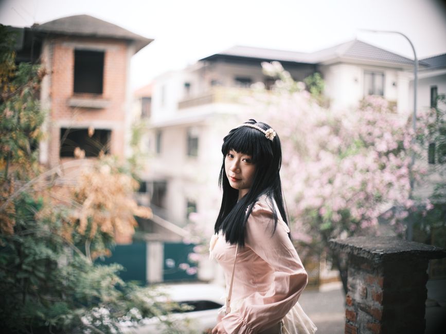 Elegant portrait of a woman amidst spring blossoms on a street in Vietnam. Captured outdoors.