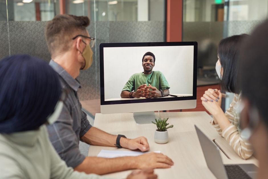 A diverse group having a video conference meeting in an office setting, promoting teamwork and collaboration.