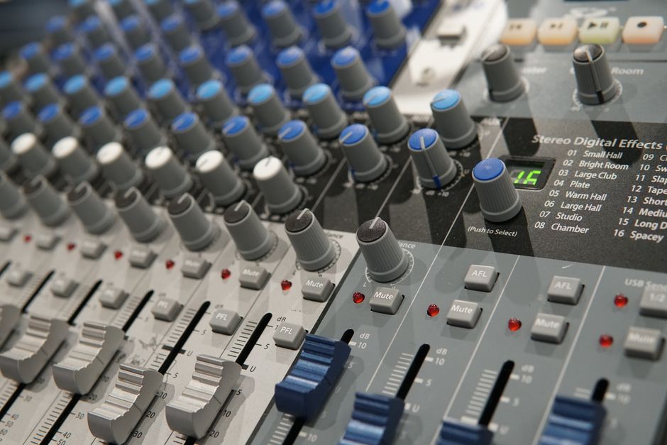 Detailed view of a modern audio mixing console with knobs and faders for sound engineering.