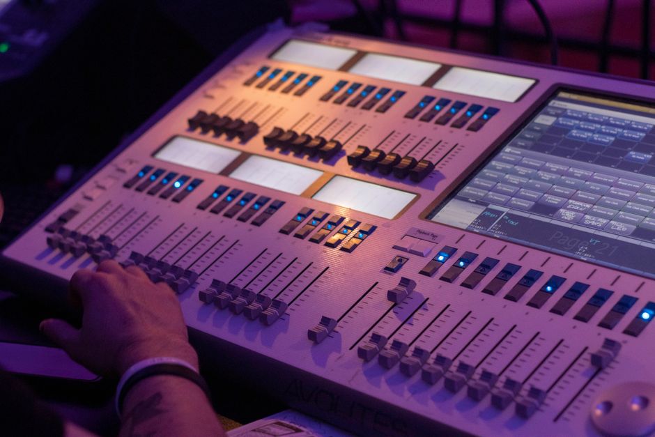 Close-up of a professional audio console in a dimly lit studio.
