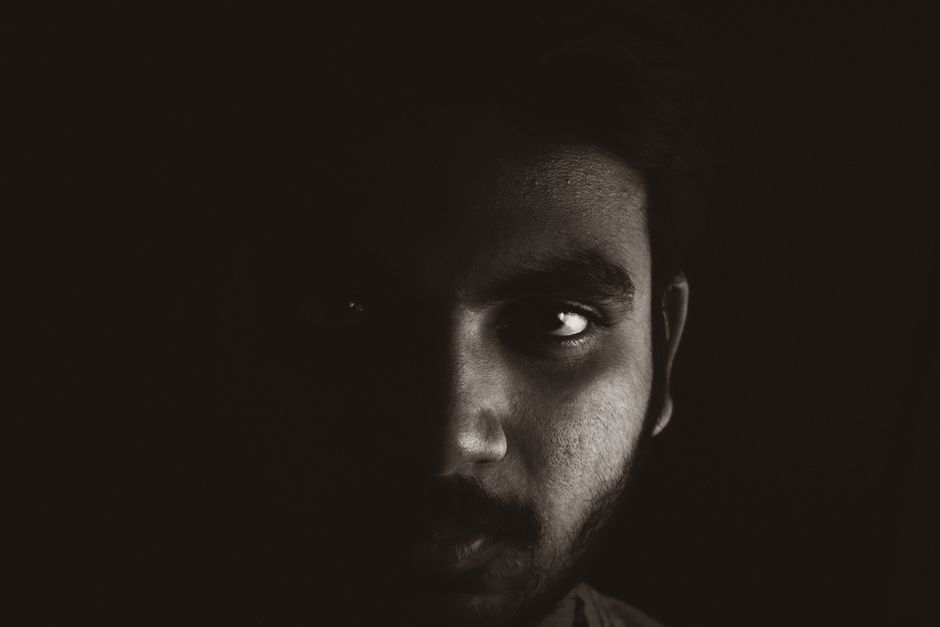 Close-up black and white portrait highlighting intense expression in a dark studio setting.