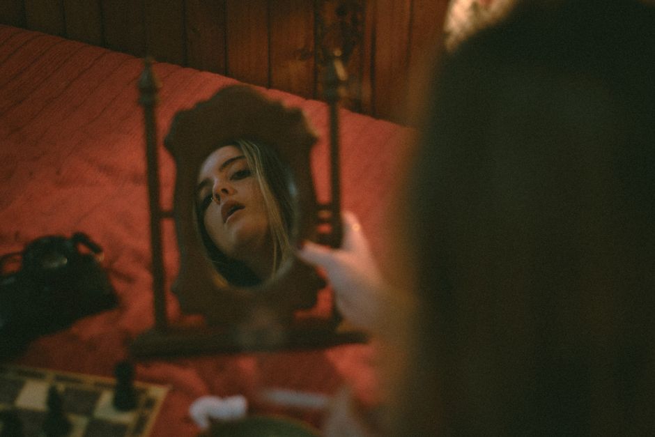 A woman is reflected in an ornate vintage mirror creating a moody artistic portrait.