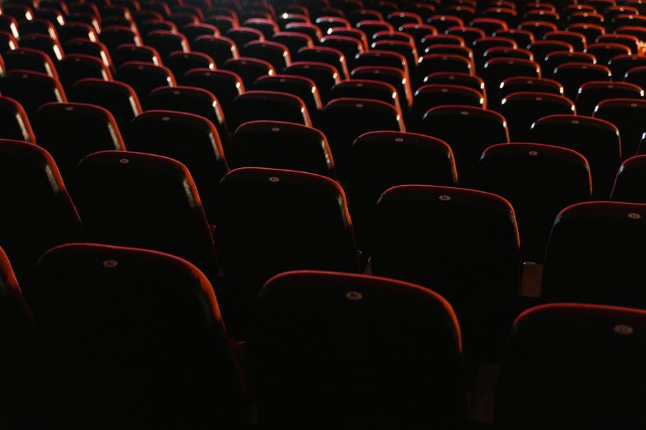 Rows of empty red seats in a dimly lit movie theater, showcasing a cinema environment.